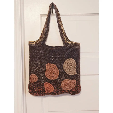Crocheted brown tote bag with spiral shell-like decorations in lighter shades.