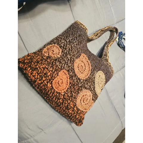 Crocheted brown tote bag with spiral shell-like decorations in lighter shades.