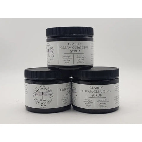 Jars of Clarity Cream Cleansing Scrub skincare product stacked in a pyramid formation.