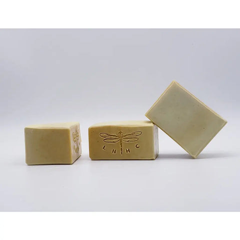 Handmade soap bars with a dragonfly logo stamped on one.