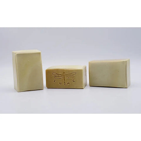 Handmade soap bars with a dragonfly logo stamped on one.