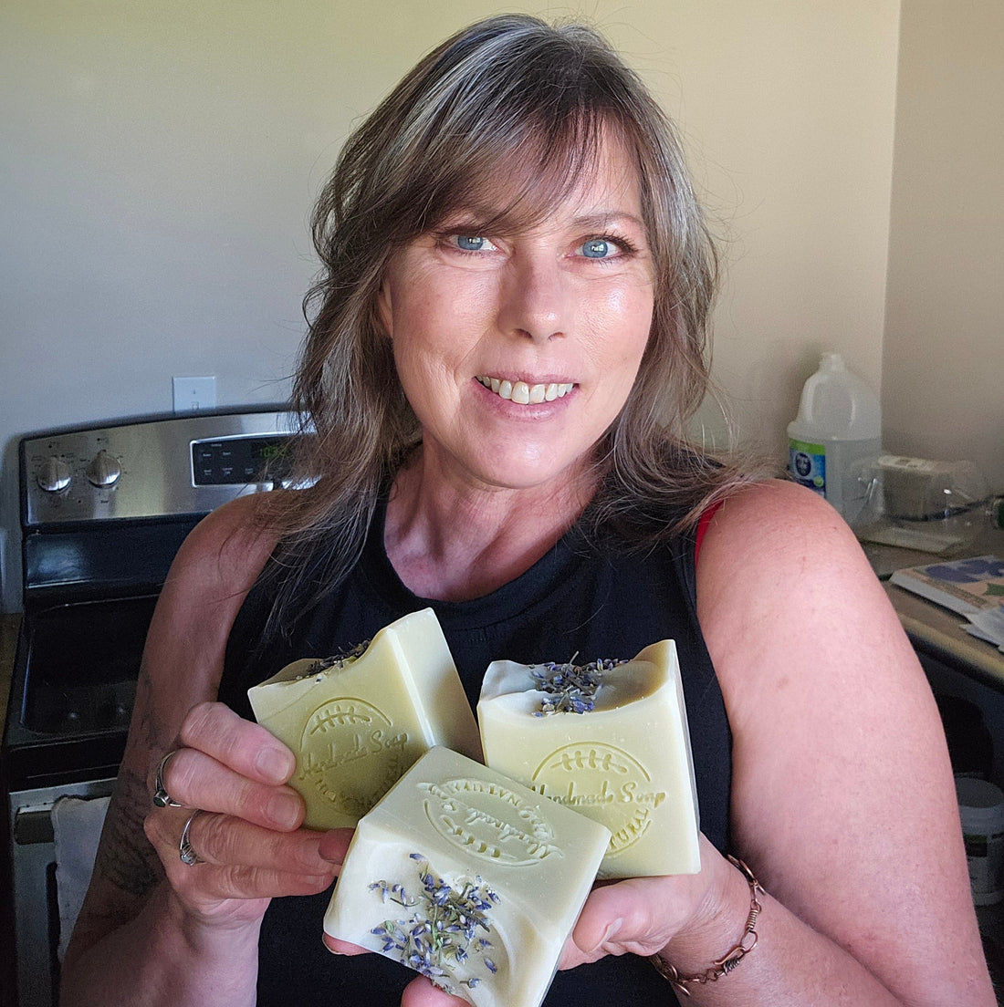 Lisa from Lisa's Natural Herbal Creations holding three bars of her handmade lavender herbal soap