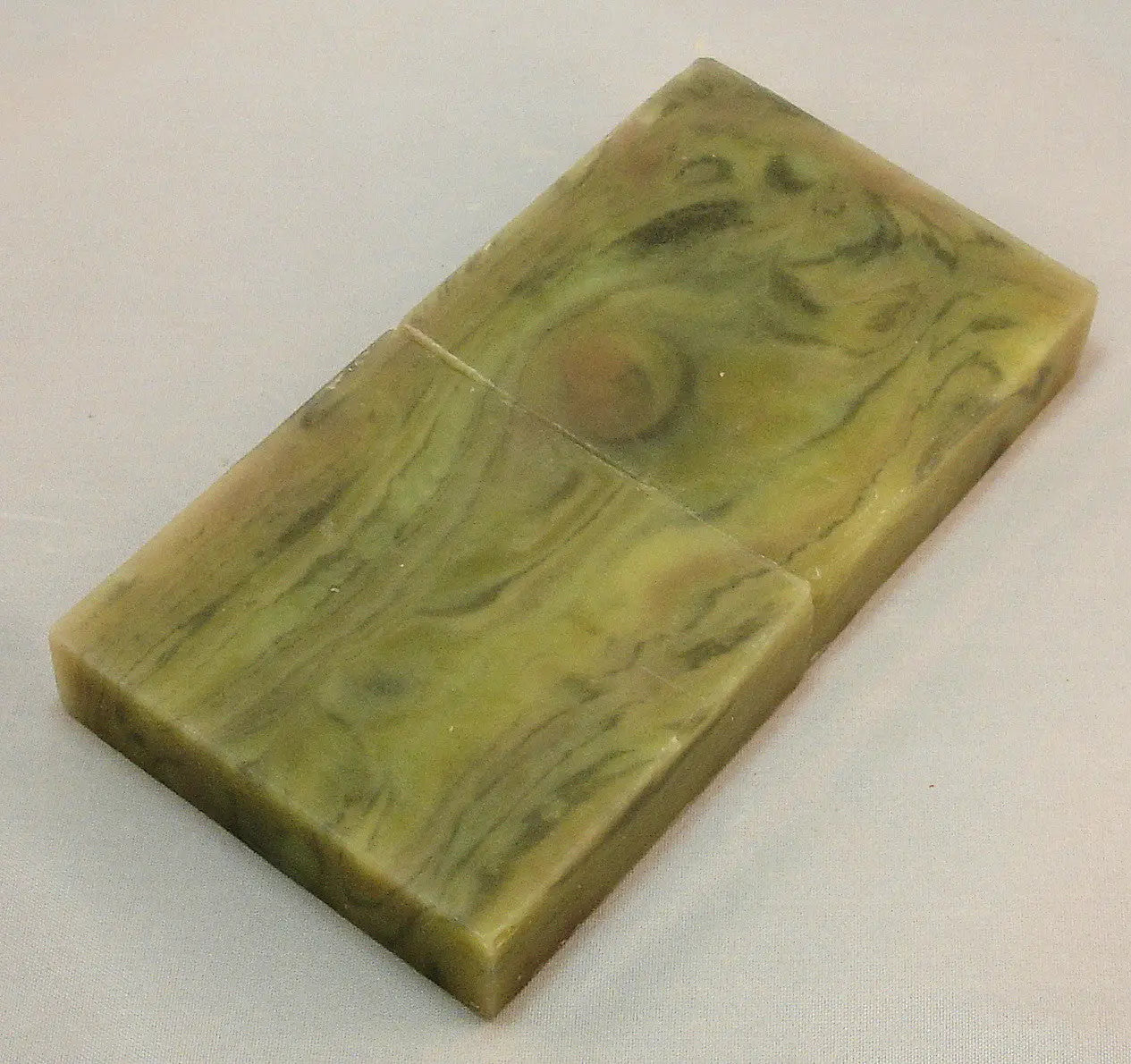 Bar of marbled green soap with swirling patterns.