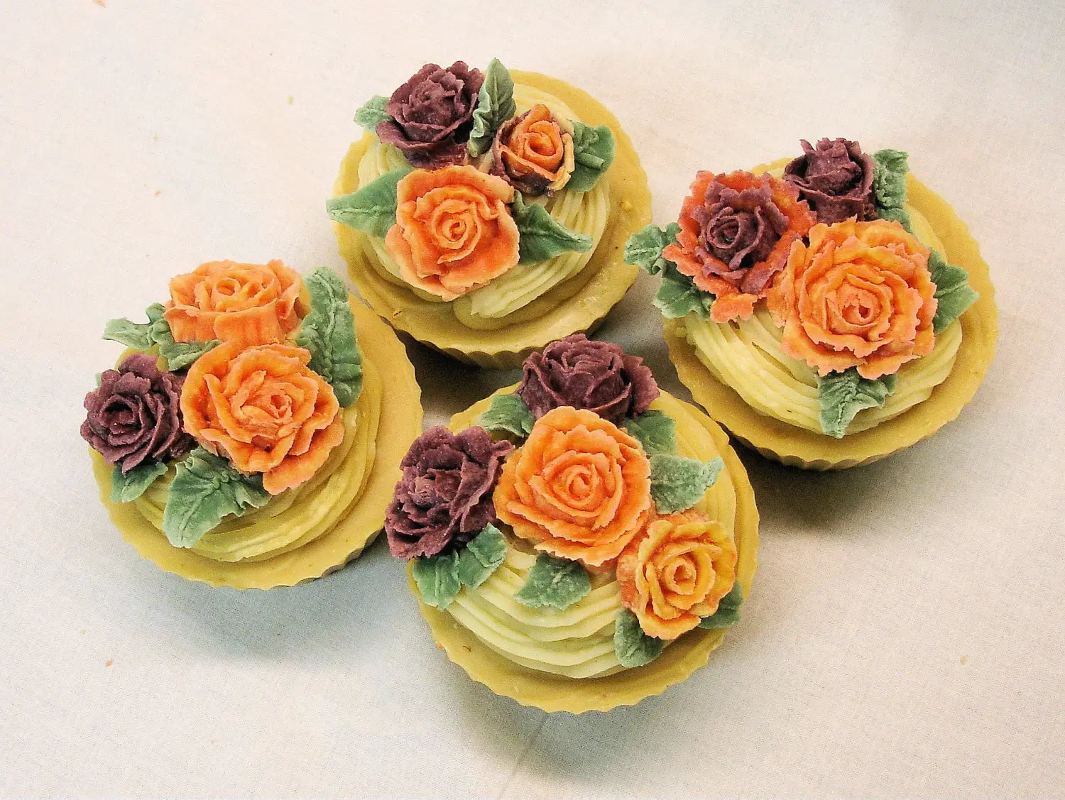 Decorative cupcakes topped with colorful soap flowers resembling roses.