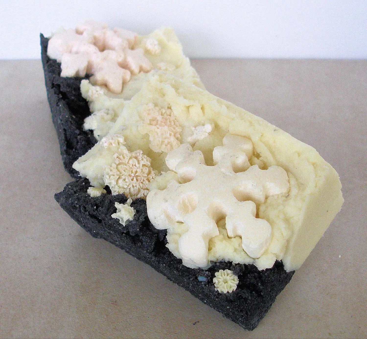 Decorative soap bar with black base and white snowflake-shaped embellishments.