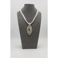 Elegant pendant necklace featuring a silver-toned oval design with a tree of life motif on a white cord.