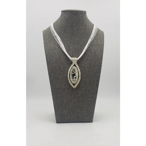 Elegant pendant necklace featuring a silver-toned oval design with a tree of life motif on a white cord.