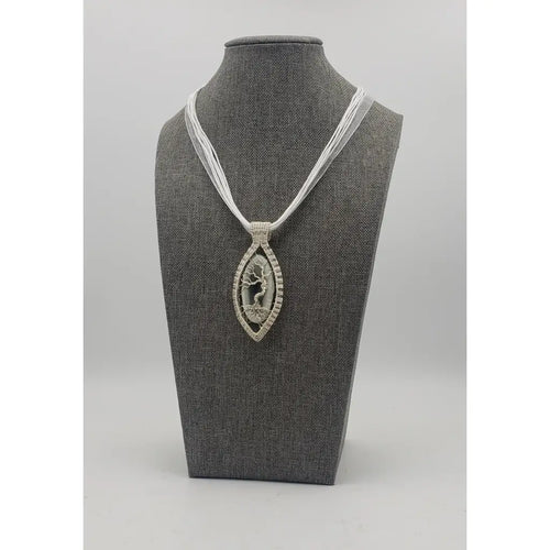 Elegant pendant necklace featuring a silver-toned oval design with a tree of life motif on a white cord.