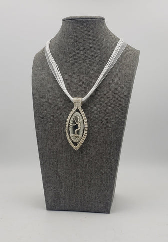 Elegant pendant necklace featuring a silver-toned oval design with a tree of life motif on a white cord.