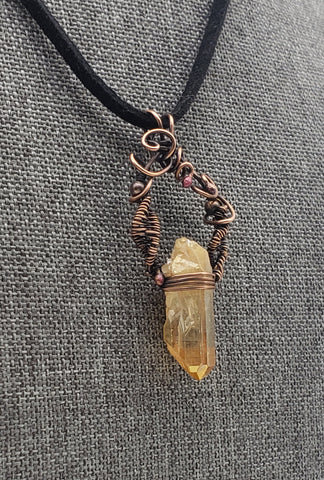 Crystal pendant necklace with intricate wire wrapping and a black cord.