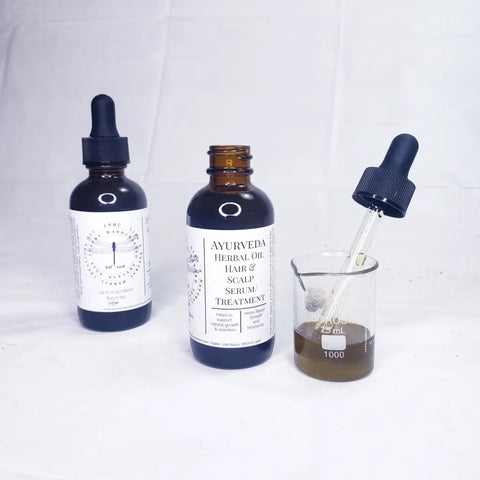 Two dark glass bottles of herbal hair and scalp treatment products with dropper caps.