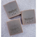 Three square bars of soap with dragonfly  imprints on their surfaces.