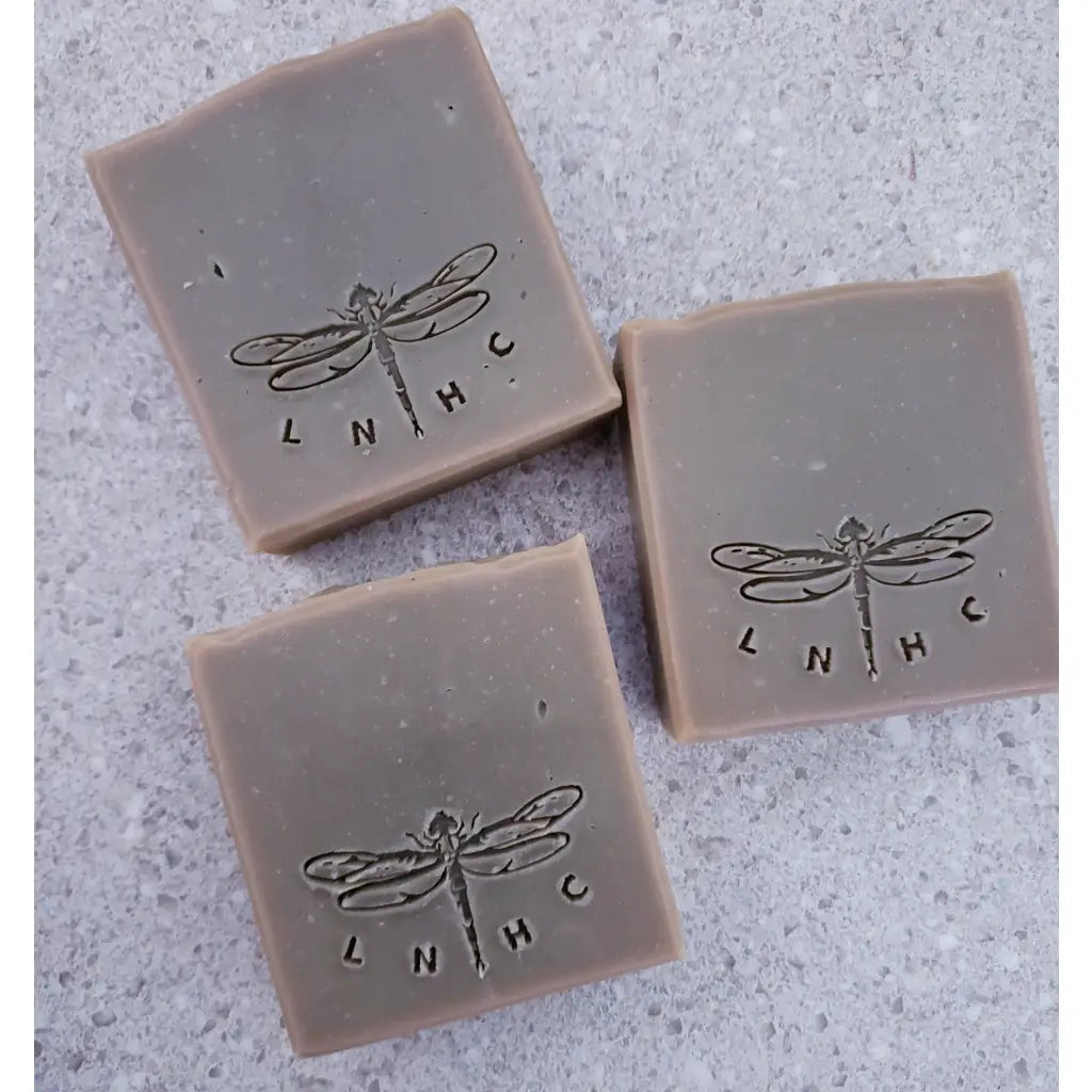 Three square bars of soap with dragonfly  imprints on their surfaces.