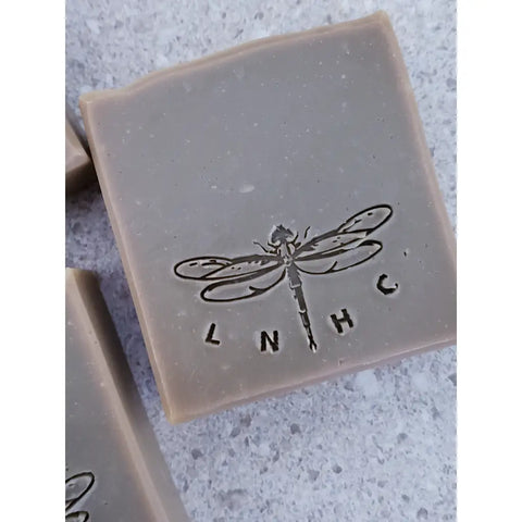 Three square bars of soap with dragonfly imprints on their surfaces.