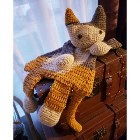 Crocheted cat-like stuffed toy with gray, yellow, and white yarn.