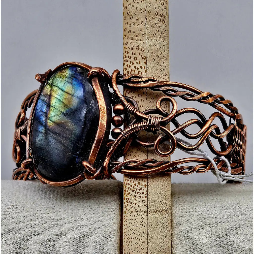 Copper wire wrapped cuff bracelet with a large labradorite cabachon with flashy labradorescence. celtic braided style copper work. Side view of the cuff