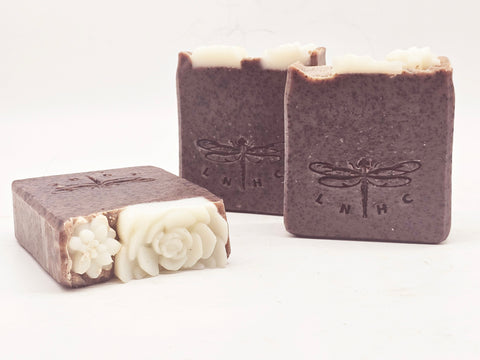 Handmade soap bars with dragonfly imprints and decorative floral designs.