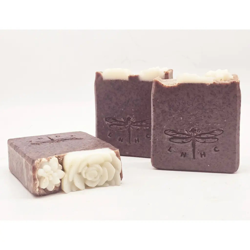 Handmade soap bars with dragonfly imprints and decorative floral designs.