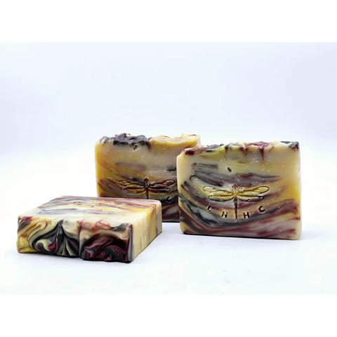 Three handmade soap bars with swirled patterns and dragonfly logos.