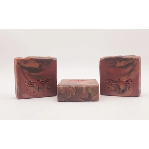 Three handmade soap bars with swirled patterns and dragonfly logos.