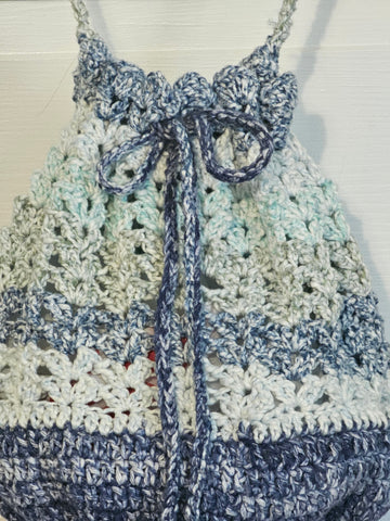 Crocheted drawstring bag with blue and white striped pattern hanging from a chain strap.s