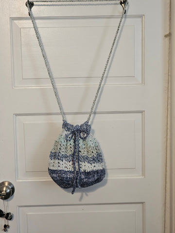 Crocheted drawstring bag with blue and white striped pattern hanging from a chain strap.