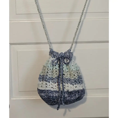 Crocheted drawstring bag with blue and white striped pattern hanging from a chain strap.