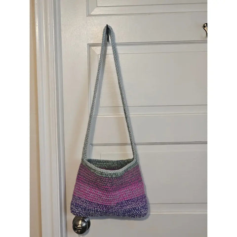 Crocheted shoulder bag with stripes in purple, pink, and gray colors.
