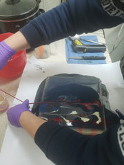 Dark-colored backpack with glossy colorful design showcasing acrylic string pull technique