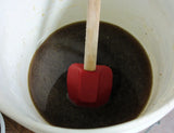 Dark thick liquid in a white bowl stirred with a red and tan spatula for the Rimmed Soap Challenge