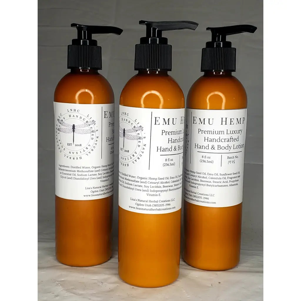 Three amber-colored bottles of EMU Hemp premium luxury hand and body lotion with pump dispensers.