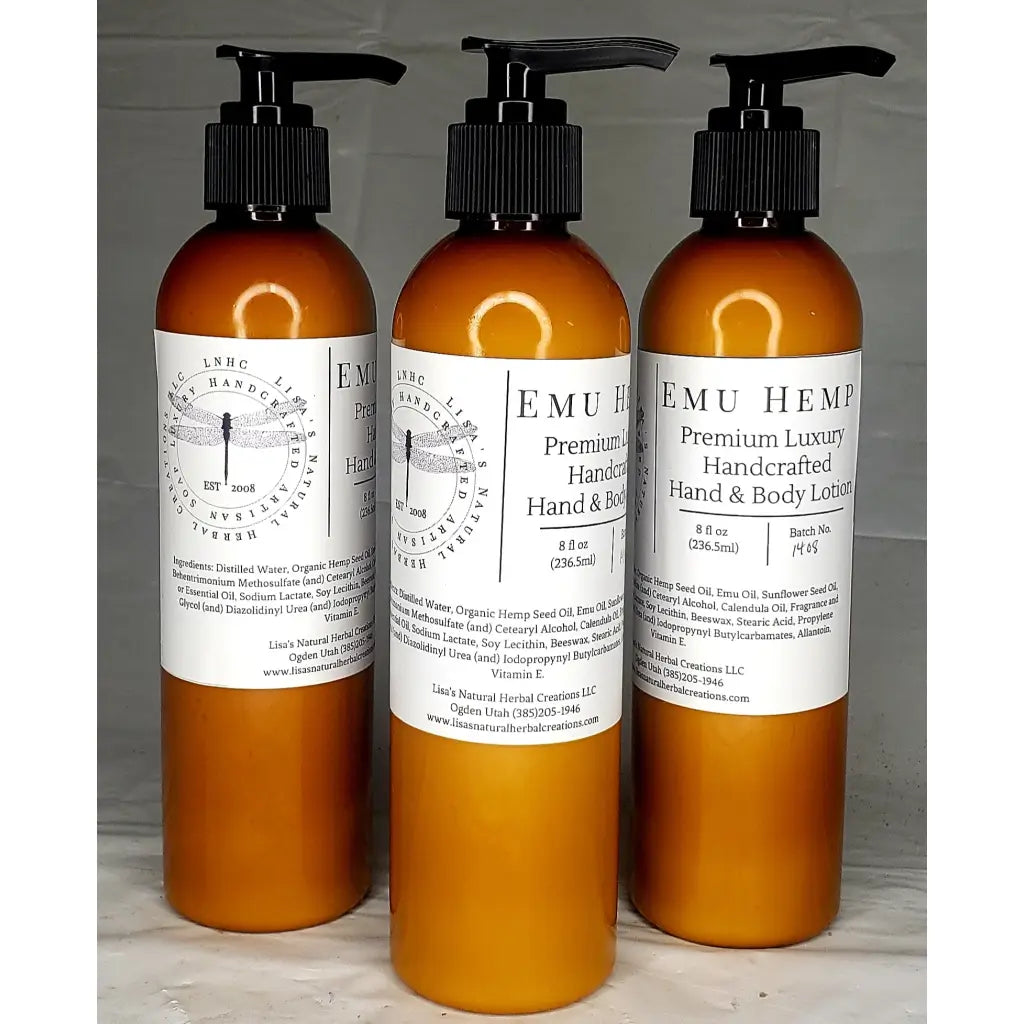 Three amber-colored bottles of EMU Hemp premium luxury hand and body lotion with pump dispensers.