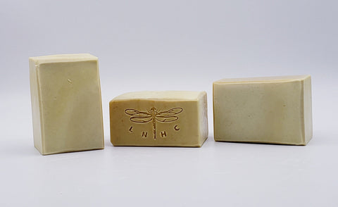 Handmade soap bars with a dragonfly logo stamped on one.