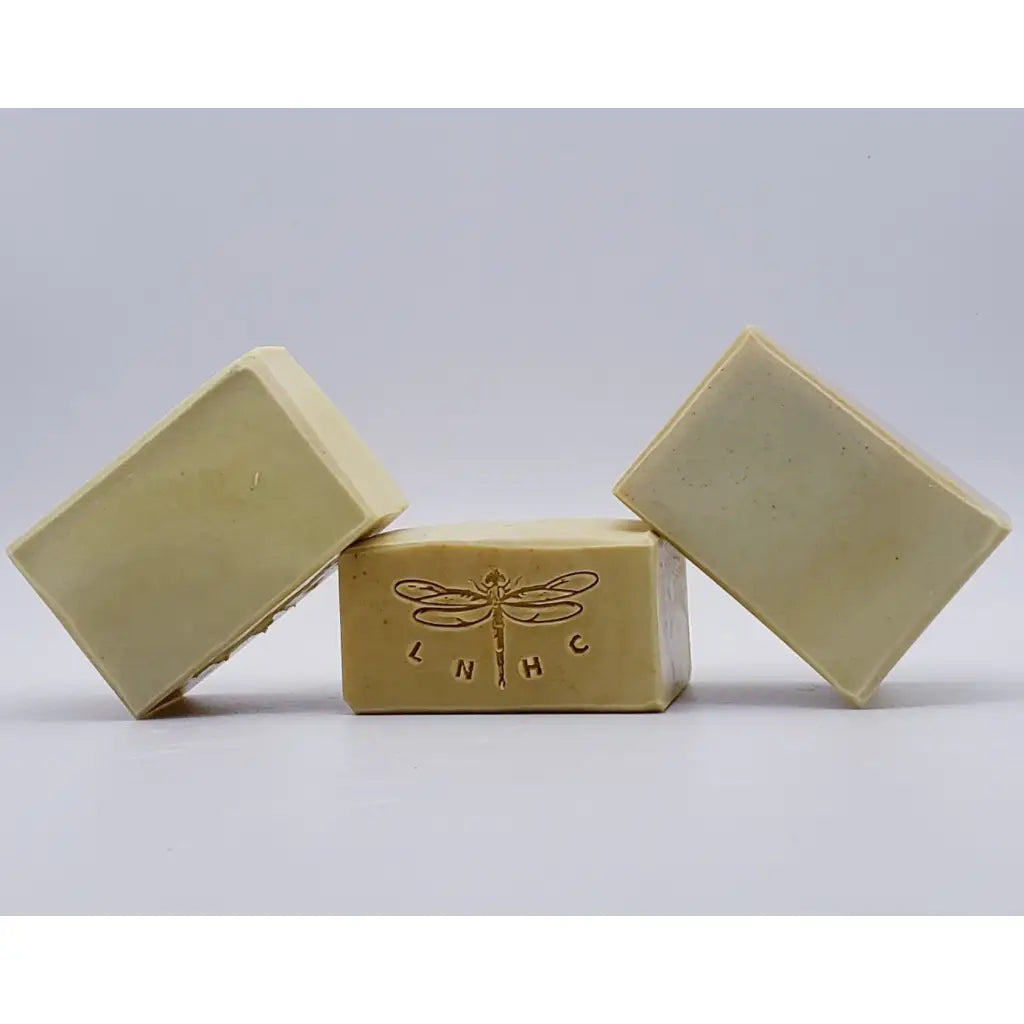 Handmade soap bars with a dragonfly logo stamped on one.