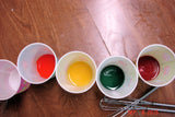 Colorful liquid dyes in small cups for soap challenge featuring oatmeal milk and shea butter