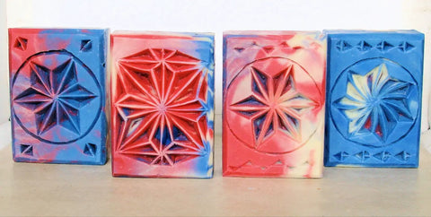 Four carved soap bars in red, white, and blue with star designs, showcasing wood chip carving craftsmanship