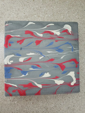 Grey square coaster with red white and blue swirled paint streaks for acrylic string pull art