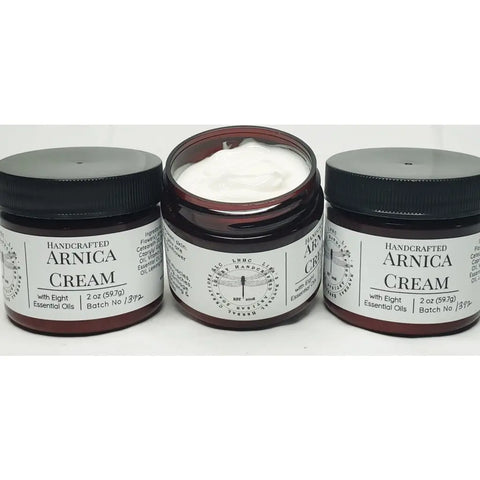 Jars of handcrafted arnica cream with black lids and labels.