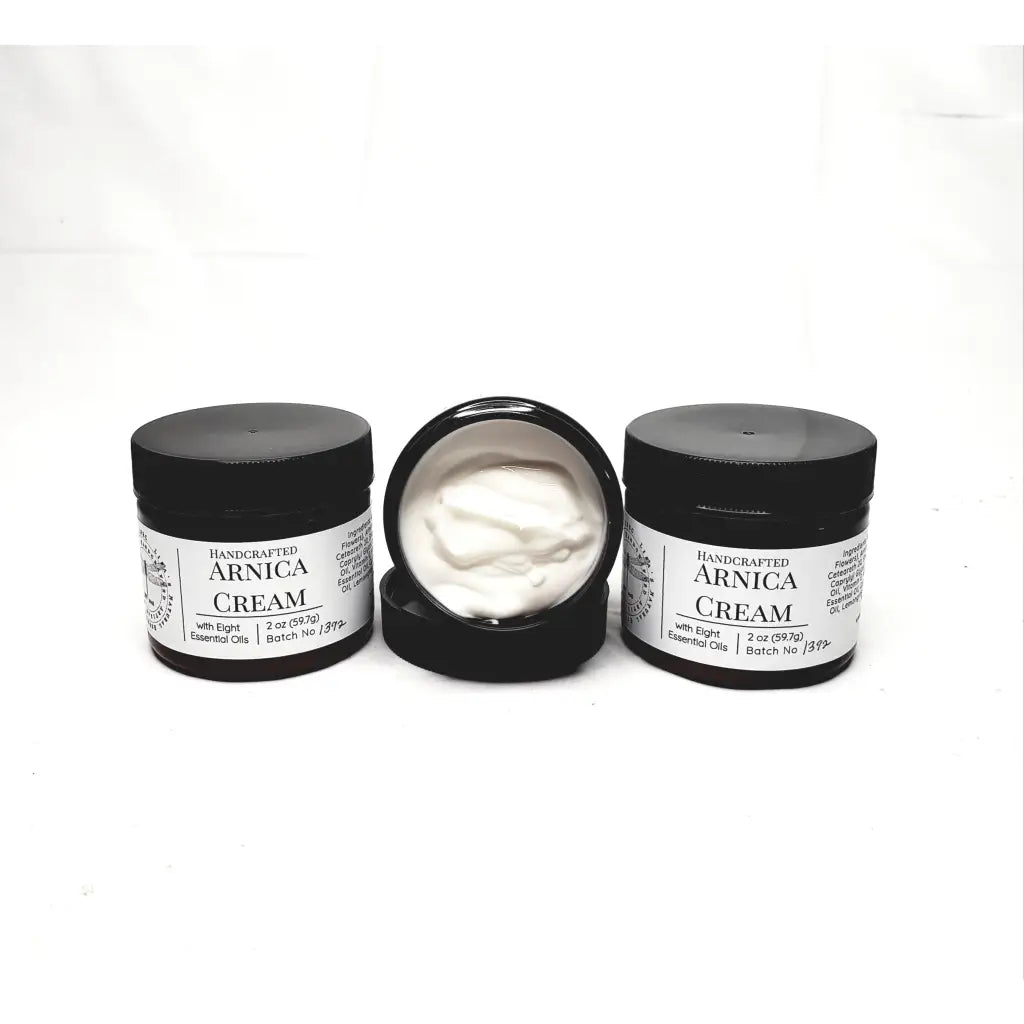 Jars of handcrafted arnica cream with black lids and labels.