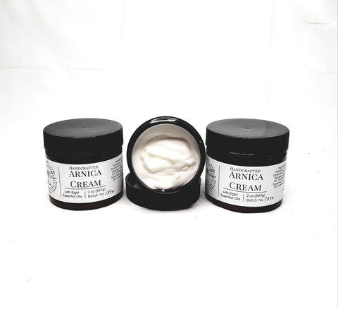 Jars of handcrafted arnica cream with black lids and labels.