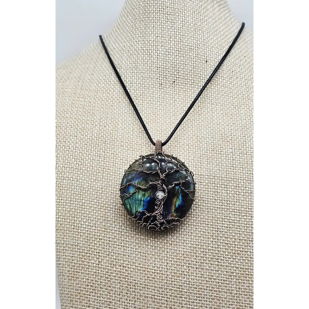 wire wrapped Labradorite & Copper Tree of Life Pendant with a selentie stone bead in the trunk. Front view of the pendant on a beige display.