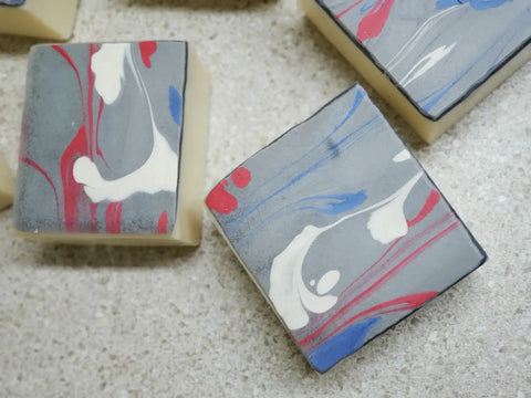 Handmade soap bars with marbled gray, red, white, and lapis blue acrylic string pull design