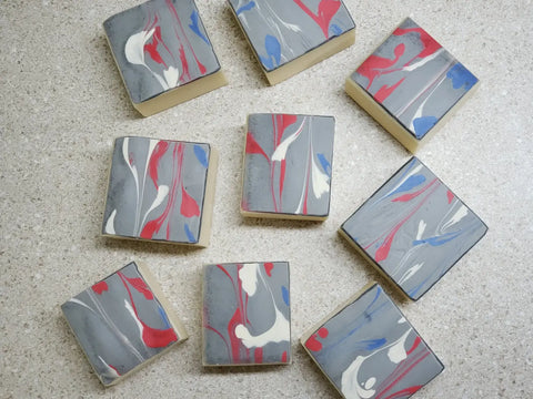 Marbled grey, red, white, and blue soap bars using acrylic string pull technique for natural herbal creations