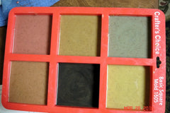 Six-cavity orange-red silicone mold with colorful cold process soap samples inspired by Arches National Park using umber brown mica