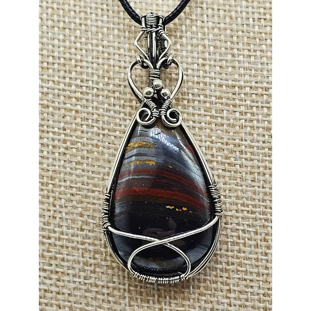 The Earth-Core Sentinel - pendant has a tear drop tirger iron cabachon wire wrapped in sterling silver