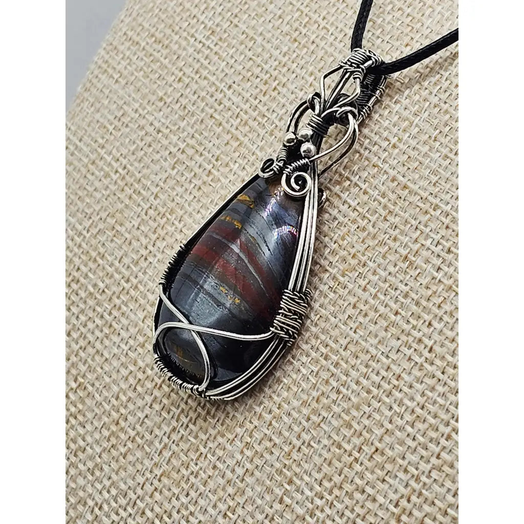 The Earth-Core Sentinel - pendant has a teardrop tiger iron cabachon intricately wire wrapped in sterling silver. side view.