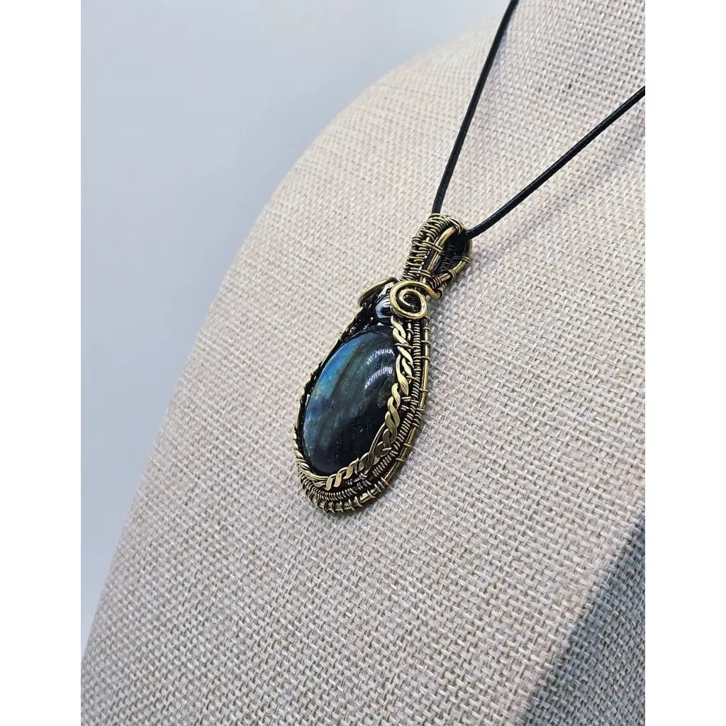 Side view, Handmade wire wrapped Labradorite & Red Brass pendant on a cord. High labradorescense showing on the labradorite. Scrolling Brass Braided wire with a hematite accent bead