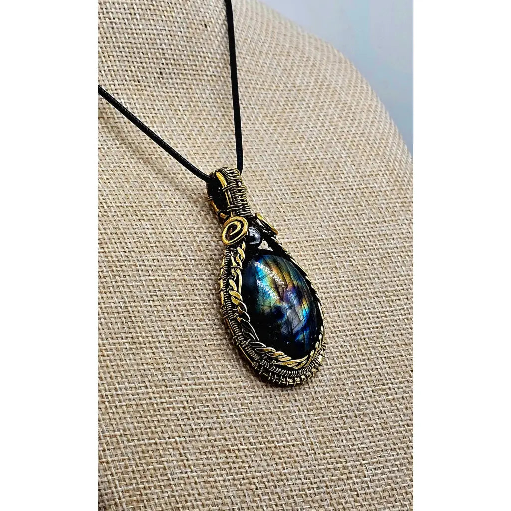 Side View, Handmade wire wrapped Labradorite & Red Brass pendant on a cord. High labradorescense showing on the labradorite. Scrolling Brass Braided wire with a hematite accent bead