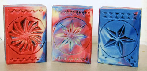 Decorative carved soap blocks in red, multicolored, and blue showcasing wood chip carving craft